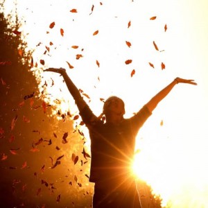 Portrait of a happy woman playing with autumn leaves in forest